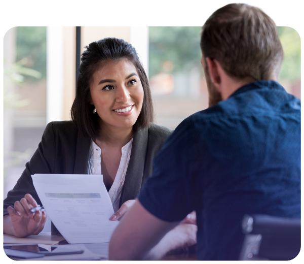 Woman holding paperwork and smiling while looking at man in meeting room