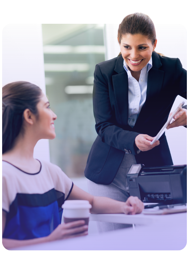 Two female associates smiling while looking at tablet