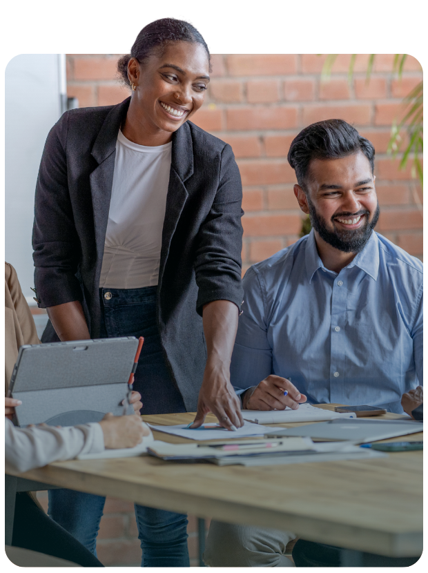 Standing female and seated male smiling at someone in meeting room