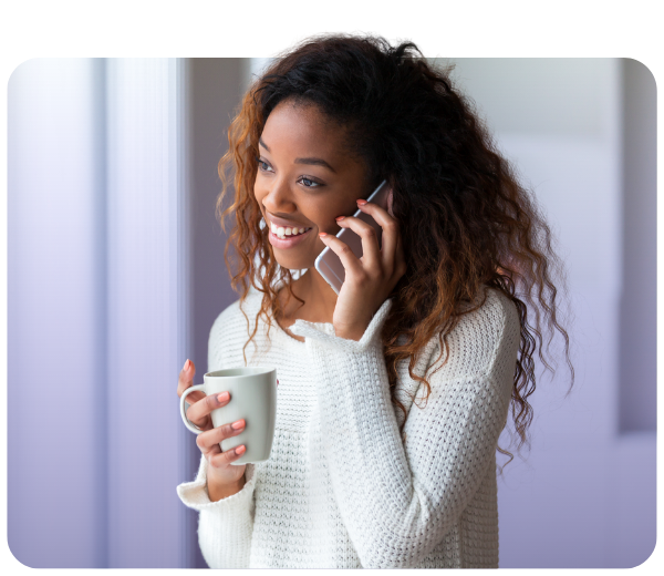 Smiling woman talking on mobile phone while holding mug