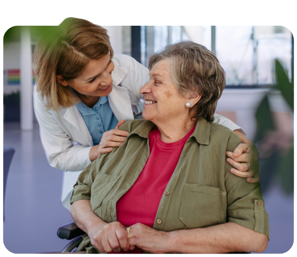 Clinician hugging patient in wheelchair from behind and smiling