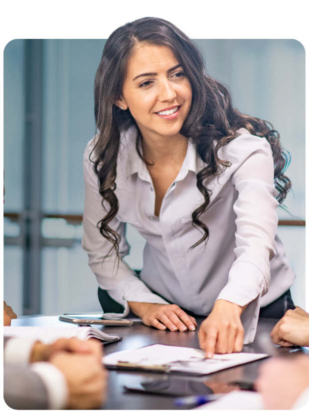 Smiling female in meeting room pointing to paper on table